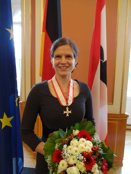 Ich mit dem Verdienstorden und einem wunderbaren Blumenstrauß vor den Flaggen Berlins, Deutschland und der EU